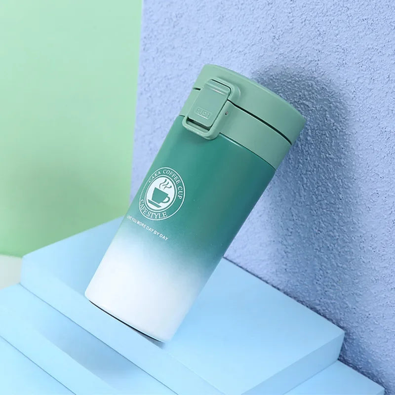 A light green double-walled stainless steel thermal travel mug resting on a blue surface.