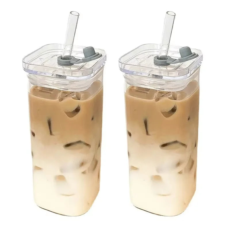 A clear glass drink cup filled with iced tea or lemonade, featuring ice cubes and a lid with a straw.