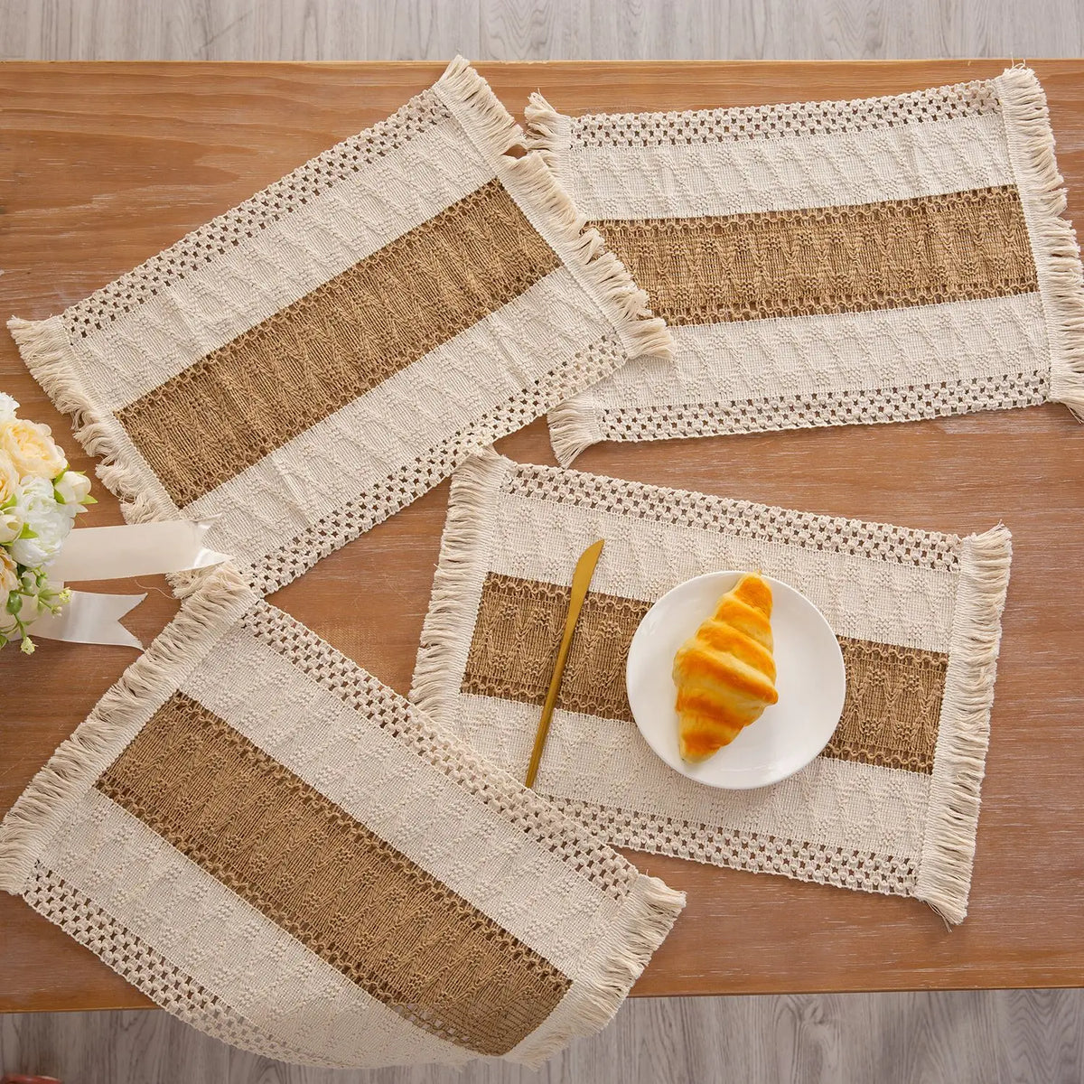 Set aus drei natürlichen Baumwoll-Burlap-Platzsets mit beige Streifen und Fransen, dekoriert mit einem Stück orangefarbener T