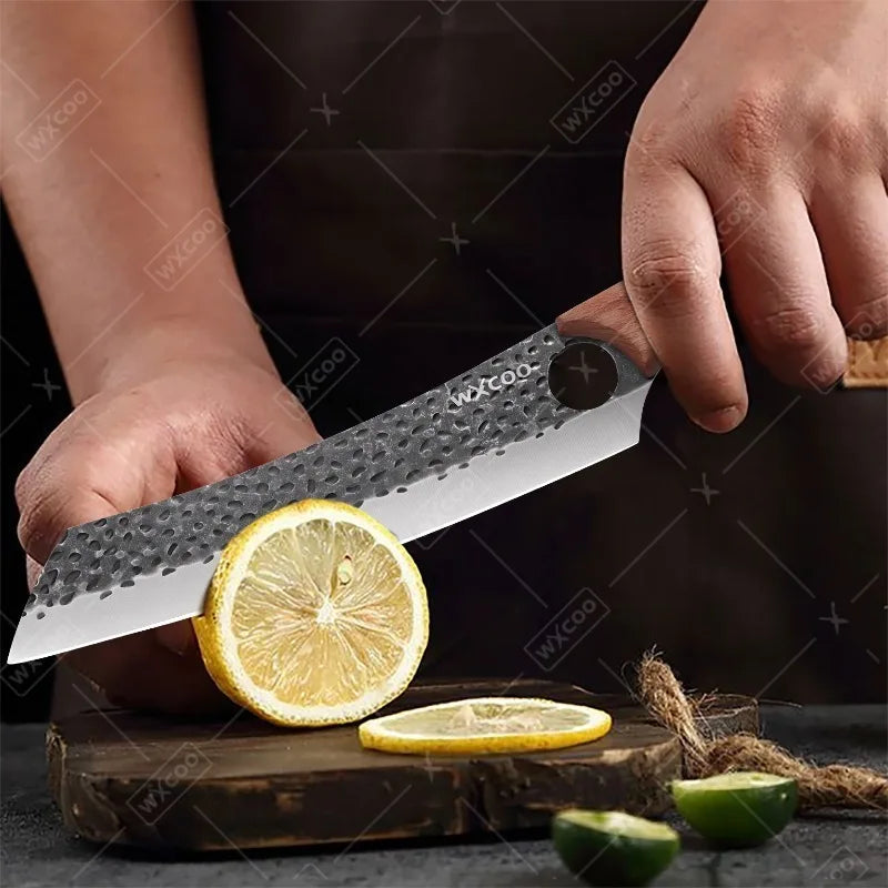 A hand is using a professional stainless steel chef knife to cut a slice of lemon on a wooden surface.