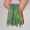 A stack of teal and gold acrylic elastic bracelets worn on a person's wrist.