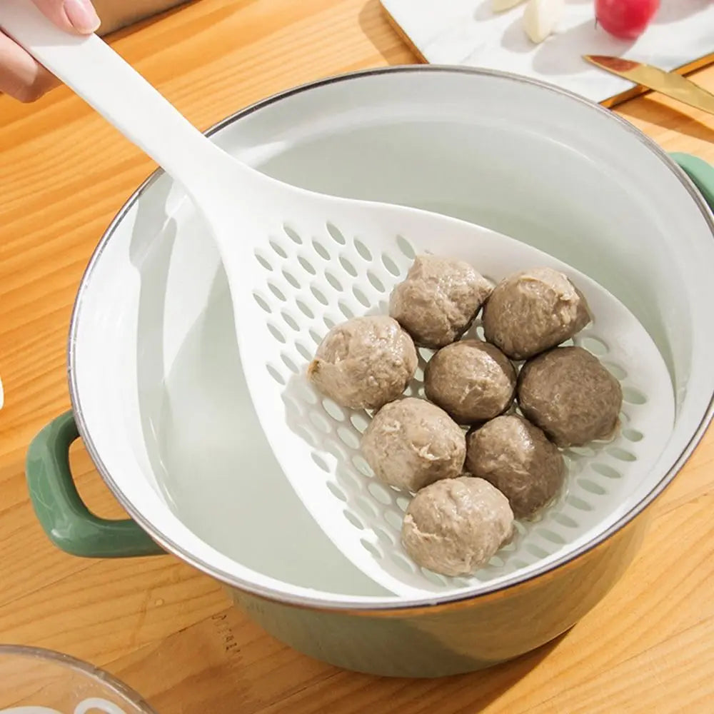 A white kitchen strainer and skimmer set is shown with several round, light brown food items inside the bowl.