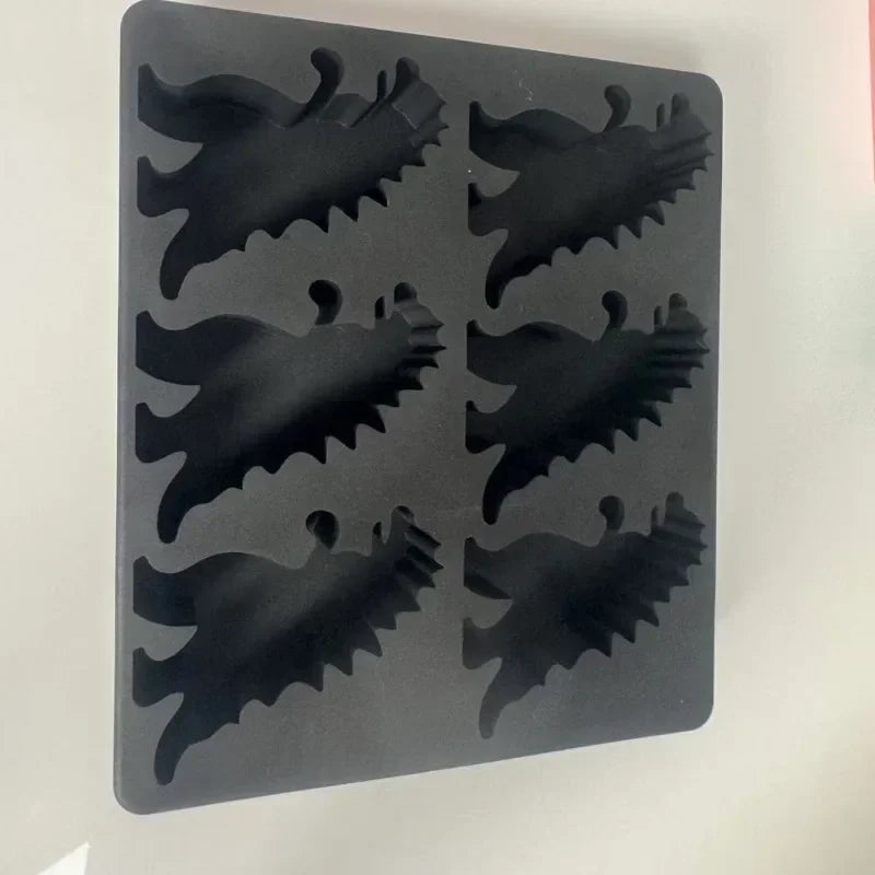A black silicone dinosaur ice cube tray set with various dinosaur shapes.