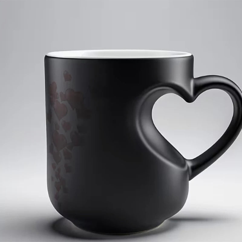 A matte black mug with a heart pattern design, shown in a studio setting.
