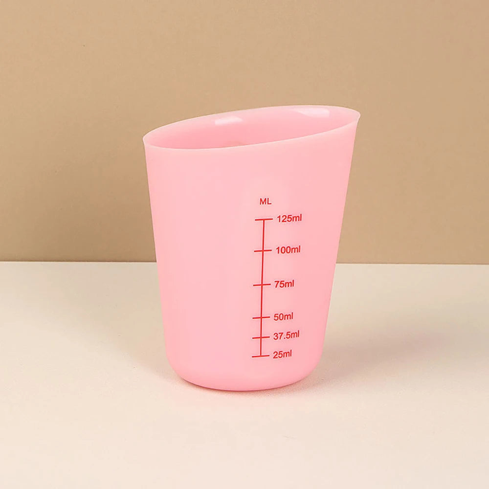 A pink silicone measuring cup with volume markings is shown against a light background.