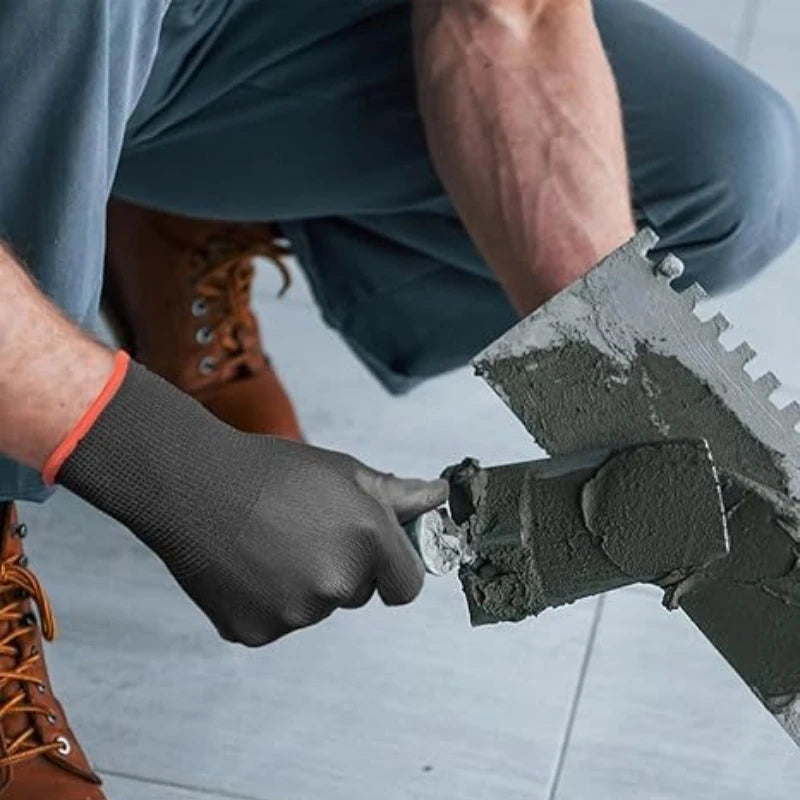 A hand wearing a dark glove is applying a gray PU coating to a surface with a trowel.