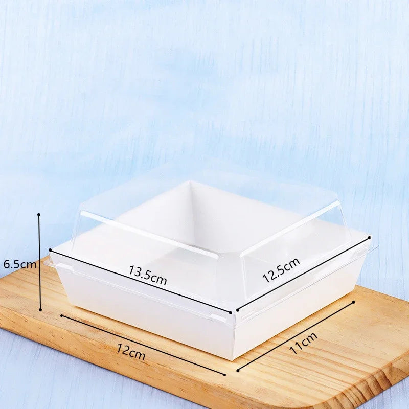 Clear square plastic food packaging boxes resting on a wooden cutting board