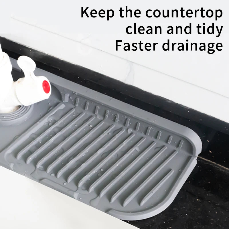 A gray silicone sink splash guard mat with ridges and a white faucet visible in a kitchen sink.