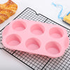 A pink nonstick silicone baking set with multiple round molds is displayed on a black grid mat.