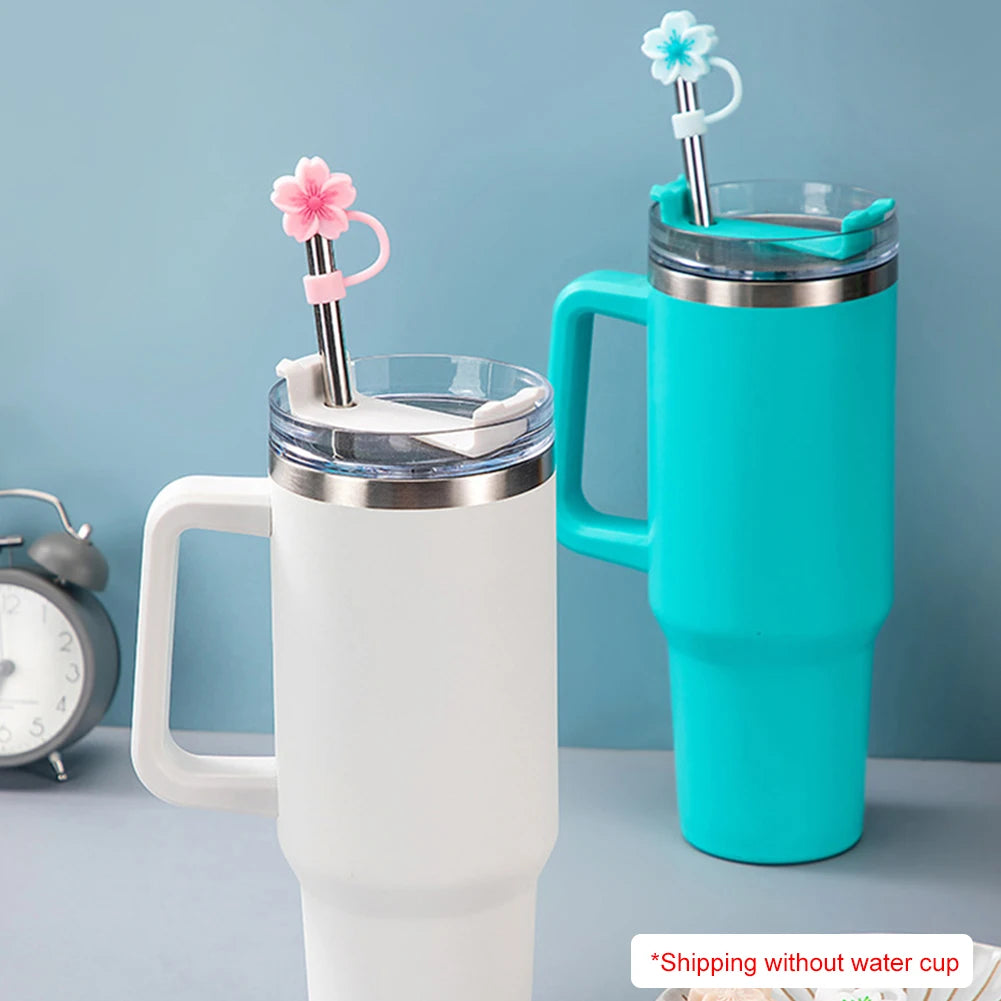 A white tumbler mug with a silicone flower straw cap and a teal colored tumbler.
