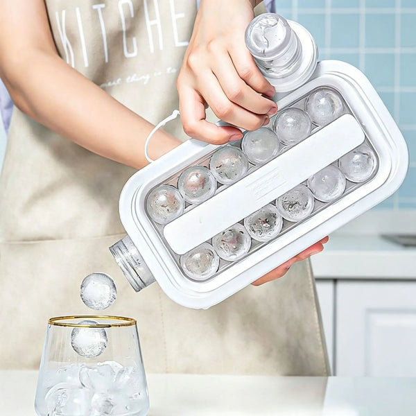 A hand is holding a white ice cube maker with twelve round ice cubes and a bottle design, pouring an ice cube into a glass.