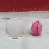 A white silicone candle mold and a pink rose-shaped object are displayed on a white surface.