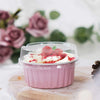 A pink dessert in a reusable aluminum foil baking cup with a clear lid topped with whipped cream and red crumbs.