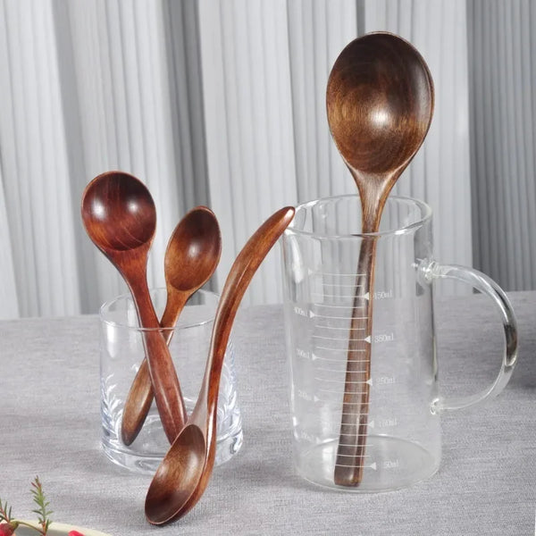 Ein Set japanischer Holzrührlöffel in einer Glastasse auf grauer Oberfläche.