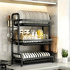 A black 3-tier vertical kitchen utensil dish rack holding plates, cutlery, and various kitchen tools.