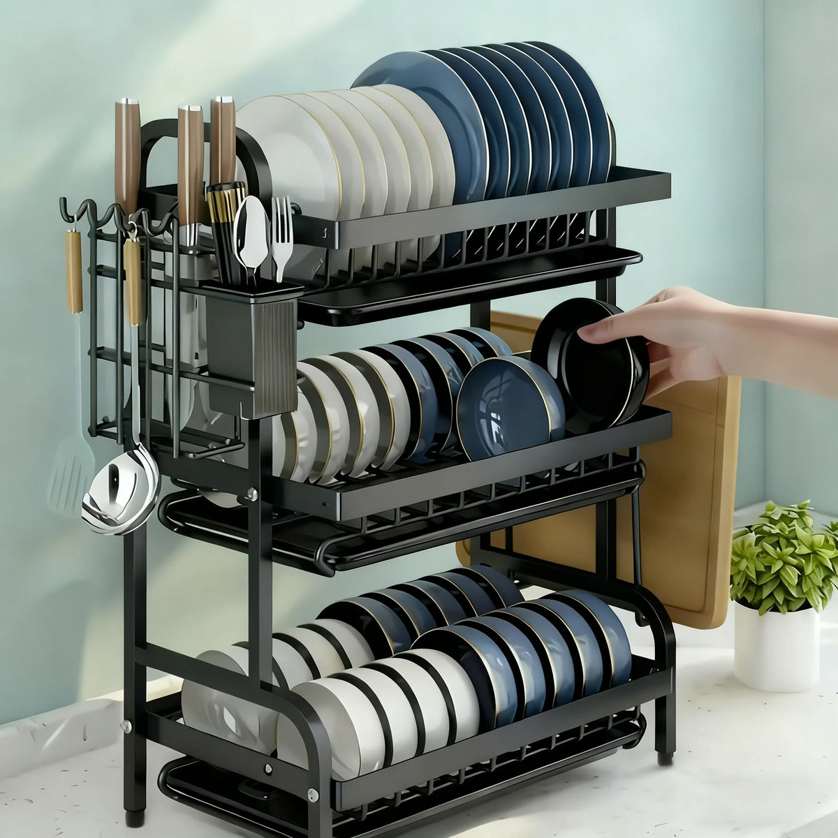 A black 3-tier vertical dish rack holding various plates and cutlery on a kitchen counter.