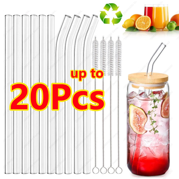 A set of reusable glass drinking straws with cleaning brushes and citrus fruit displayed next to a jar of red drink.
