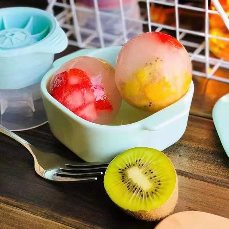 A bowl of colorful fruit spheres, including pink and yellow, next to a kiwi slice on a wooden table.