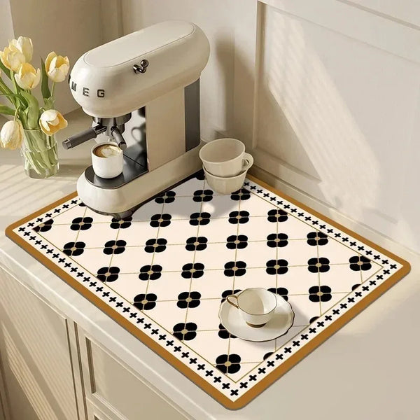 Eine weiß-schwarz gemusterte Gummidisch-Trockenmatte auf einer Arbeitsplatte neben einem Kaffeemühle.