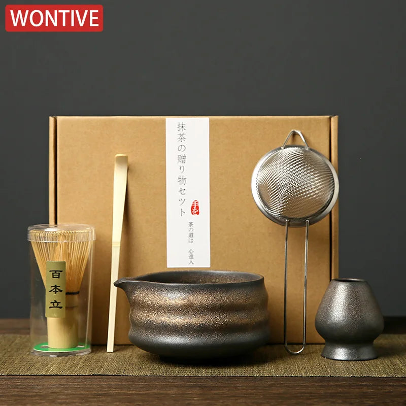 A box containing a Japanese matcha whisk set, including bamboo whisks and a metal whisk, displayed on a wooden surface.