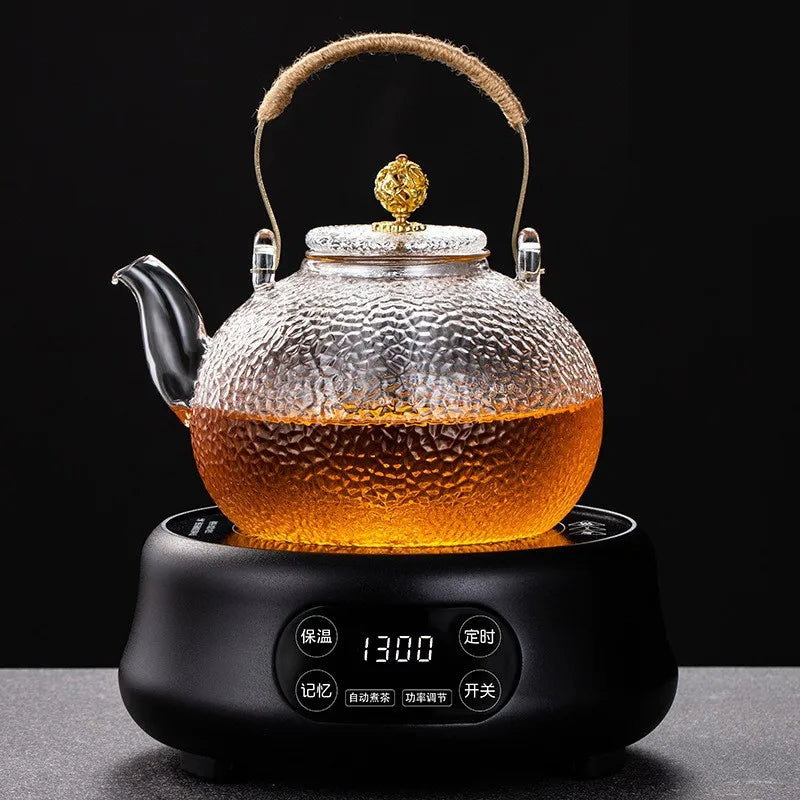 A clear glass teapot with a hemp rope handle sits on a black electric kettle base.