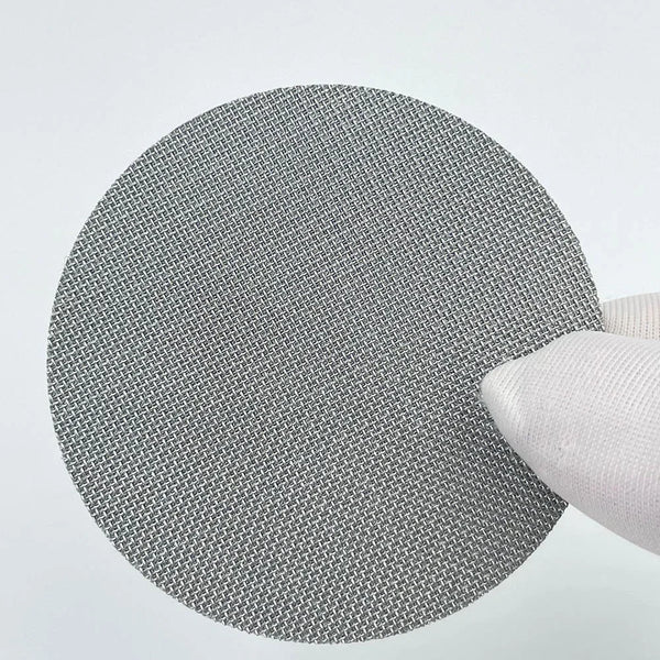 A round, gray mesh coffee filter plate replacement is shown next to a white filter holder.