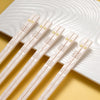 A set of five pairs of light pink reusable food-grade metal chopsticks resting on a white plate.