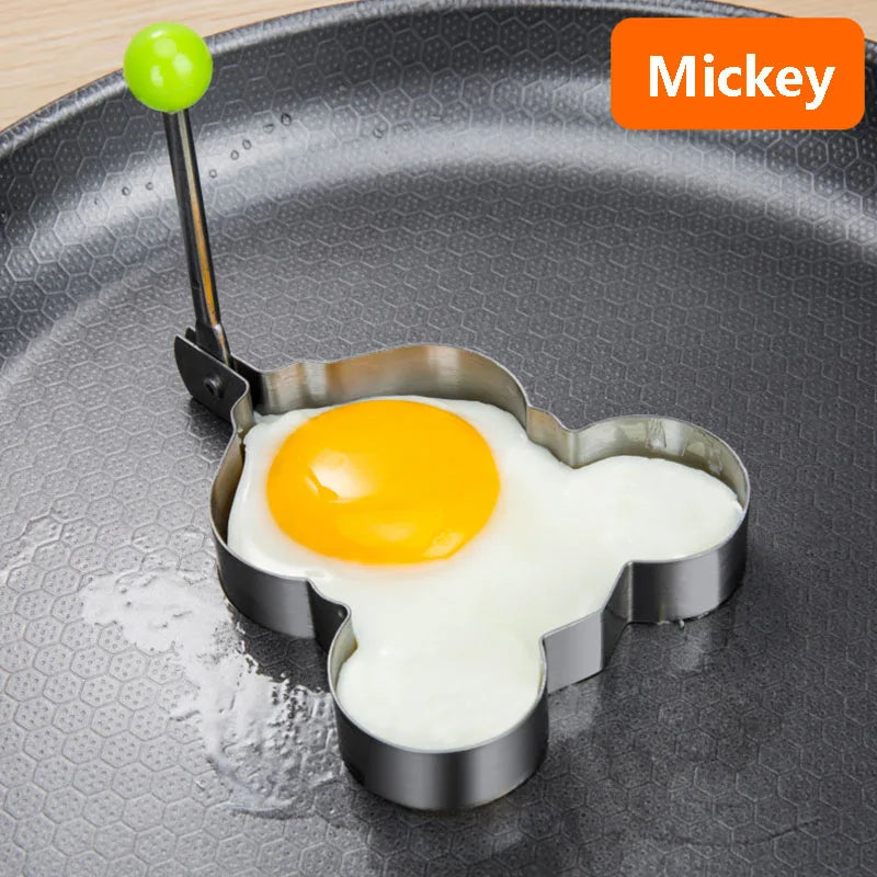 A stainless steel fried egg mold with a yolk placed inside on a dark plate.