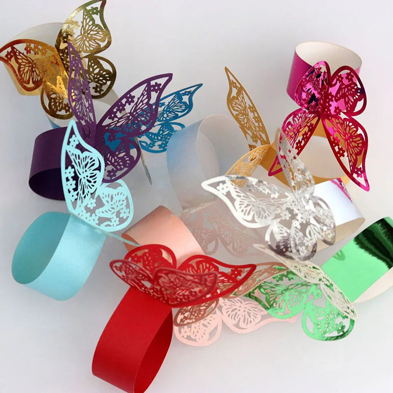A collection of colorful laser cut paper butterfly napkin rings in various shades of pink, gold, purple, and teal.