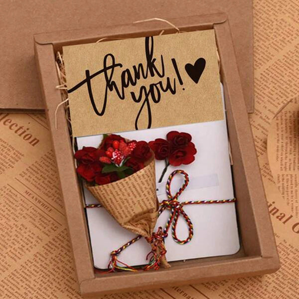 Dankeskarte in einem Holzrahmen mit handschriftlicher Nachricht und einem kleinen Strauß roter Rosen.