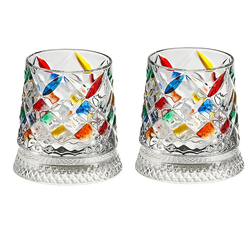 A pair of cut crystal rotating whiskey glasses filled with colorful ice and liquid.