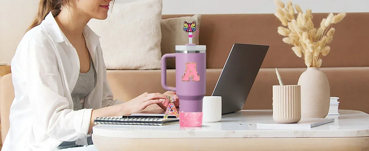 A woman is using a silicone straw cover set for tumblers on a desk with a laptop and decorative elements.