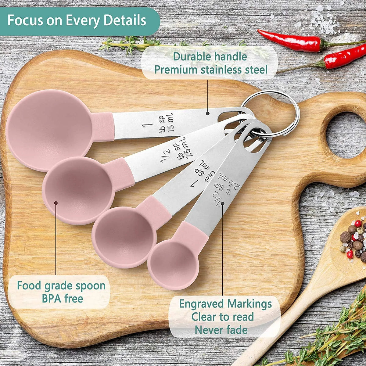 A set of pink and silver precision stainless steel measuring spoons displayed on a wooden cutting board.