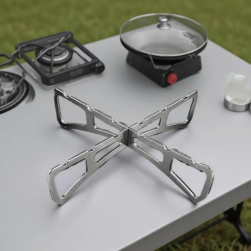 A foldable stainless steel steaming rack is placed on a table next to a portable gas burner.