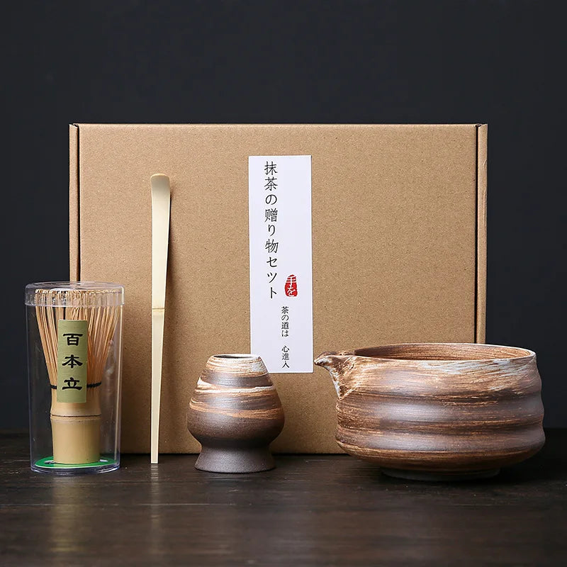 A set of Japanese matcha whisks and a ceramic teapot are displayed in a cardboard box.