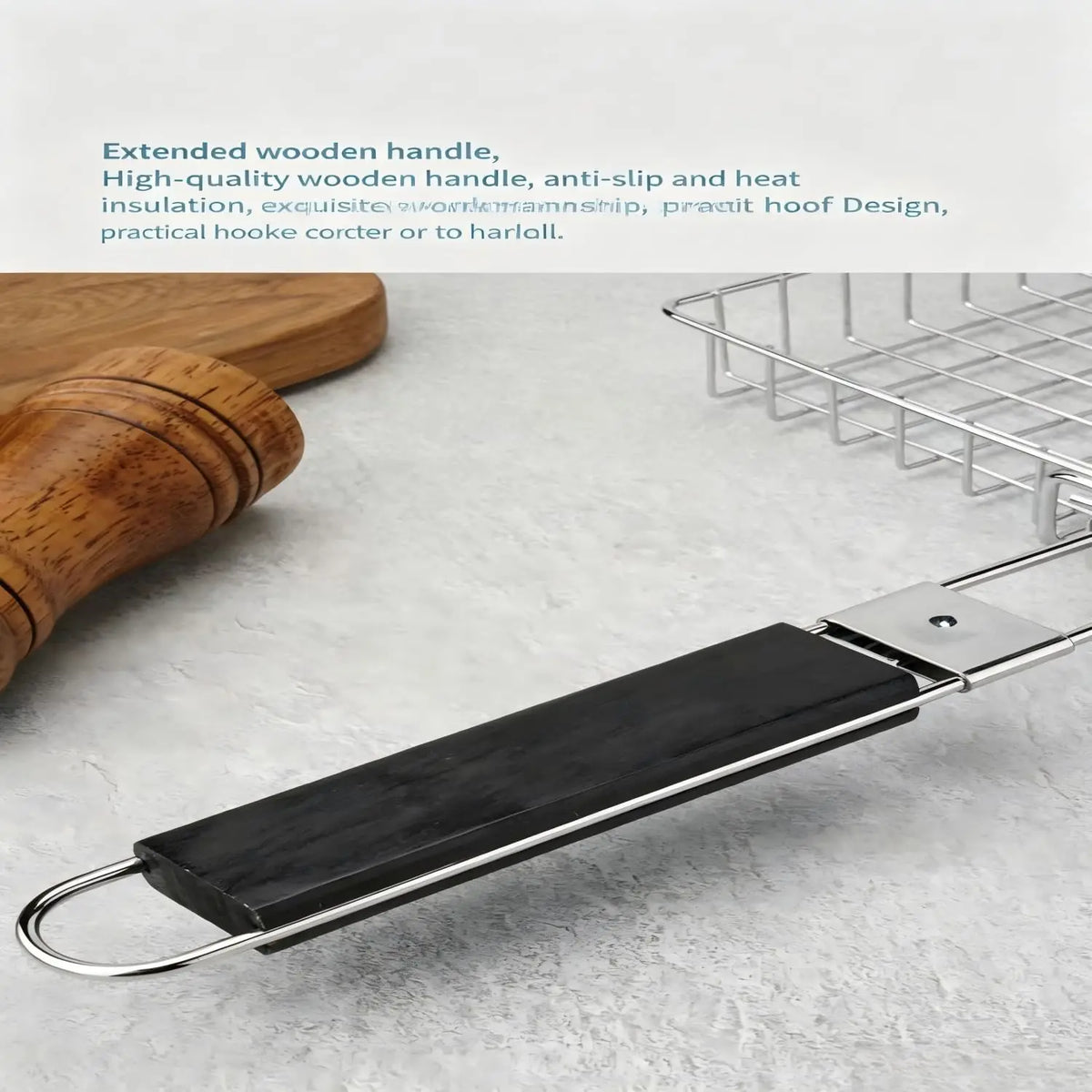 Vista de cerca de una canasta para asar de metal plateado con un mango de madera extendido, sobre una superficie gris.