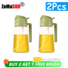 Two glass oil sprayer and pourer bottles with green lids and yellow liquid, plus one free brush.
