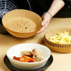 A hand is holding a silicone baking liner, with fried food and french fries visible on a table.