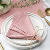 A stack of ten soft pink cotton table napkins is neatly folded on a white plate.