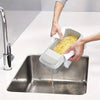 A hand is pouring cooked yellow noodles into a stainless steel electric microwave noodle cooker basin.