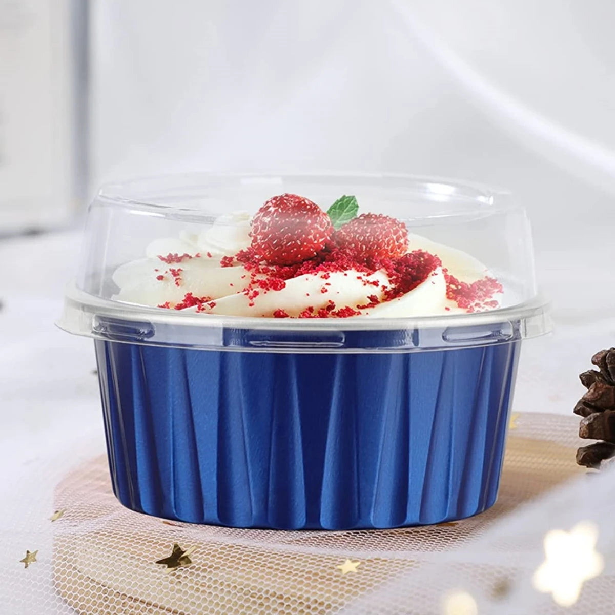 A clear reusable aluminum foil baking cup filled with whipped cream and topped with red sprinkles.