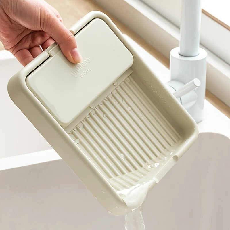 Una mano coloca un organizador de tapa para ollas blanco con diseño acanalado en un fregadero.