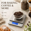 A precision digital kitchen scale is shown measuring coffee beans on a glass bowl next to baking and meal prep ingredients.