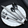 A set of stainless steel cutlery including a knife, fork, and spoon with a skull pattern design on a white plate.