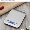 A stainless steel digital kitchen scale is displayed on a wooden surface next to some red berries.
