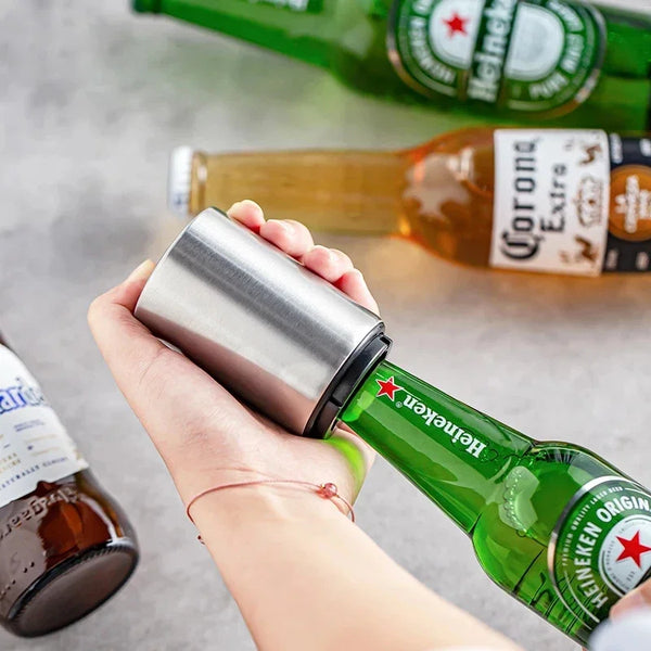 Eine Hand hält einen Edelstahl-Öffner für Bierflaschen neben einer grünen Heineken-Flasche.