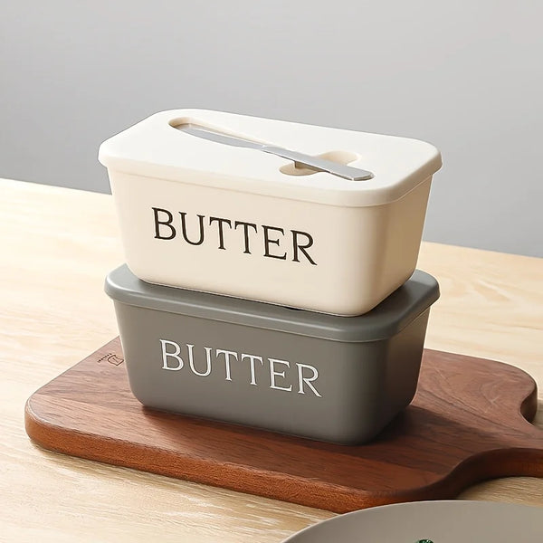 Helles beiges Butter-Aufbewahrungsgefäß mit silbernem Sägekniv resting auf einem Holzbrett.