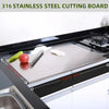 A stainless steel cutting board is shown on a kitchen counter with vegetables and a knife.