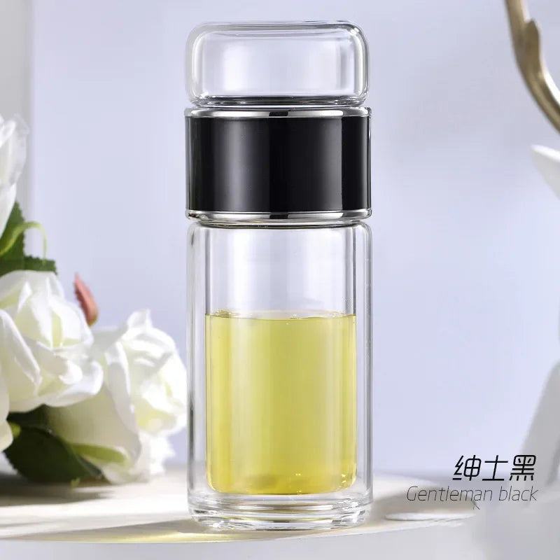 A double-layer borosilicate glass tea infuser with a black cap and yellow liquid inside.