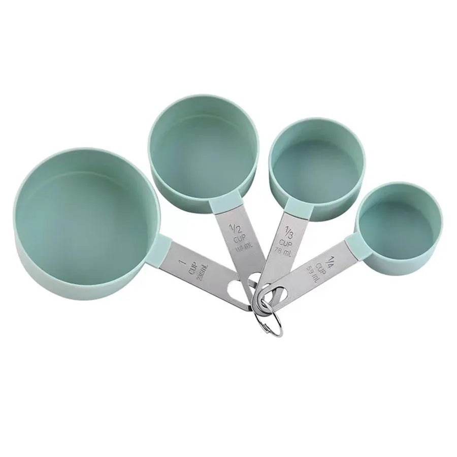 A set of stainless steel measuring cups and spoons in a muted green color.